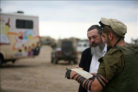 חייל מניח תפילין עם איש חב''ד, במבצע ''עופרת יצוקה'' ברצועת עזה. צילום'' מ. אלפסי, ויקיפדיה