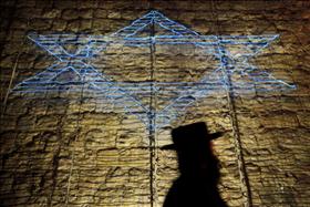 עובר אורח חרדי עובר ליד כתובת אור של מגן דוד שהוקרנה על חומות העיר העתיקה בירושלים. 28.04.2011. צילום: מרים אלסטר, פלאש 90